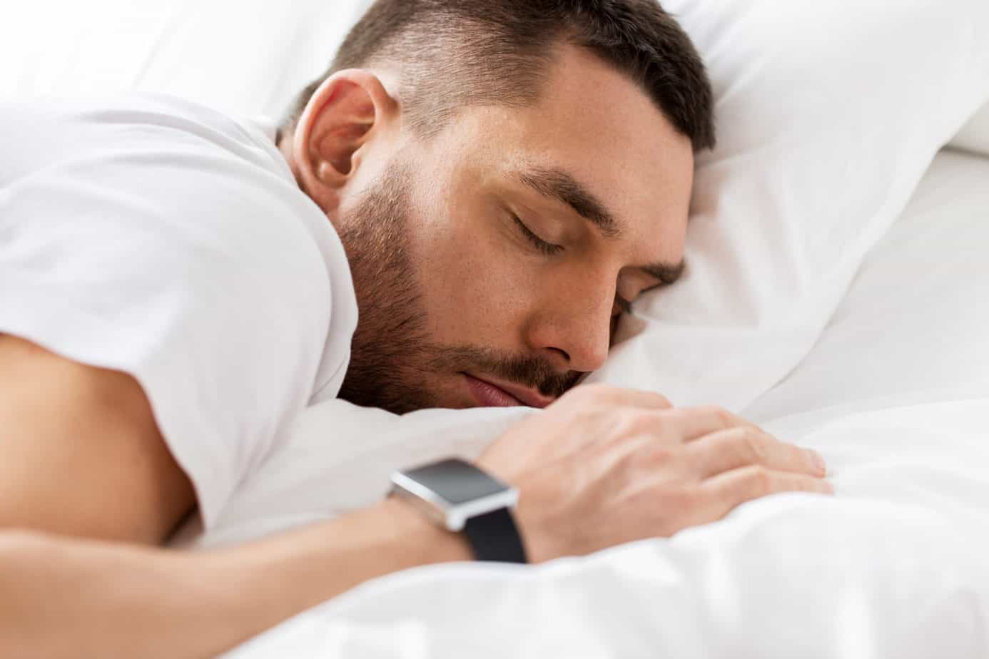 Mann trägt Fitness Tracker beim Schlafen